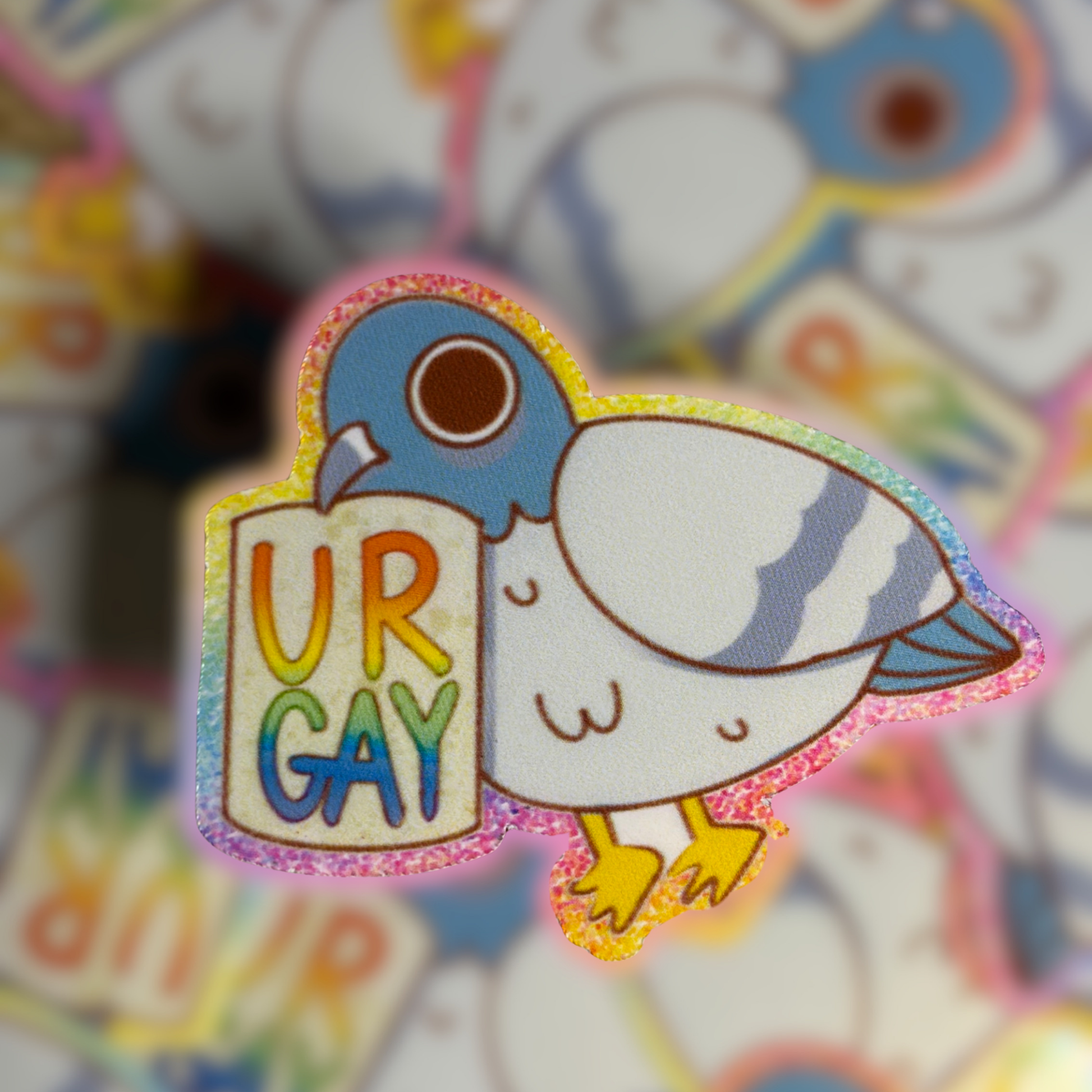 A pigeon holding a piece of paper that says Ur Gay with a rainbow background.